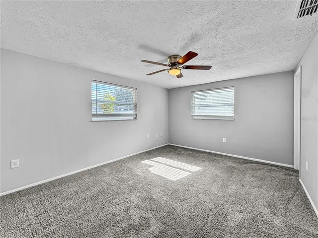 an empty room with a window and a ceiling fan