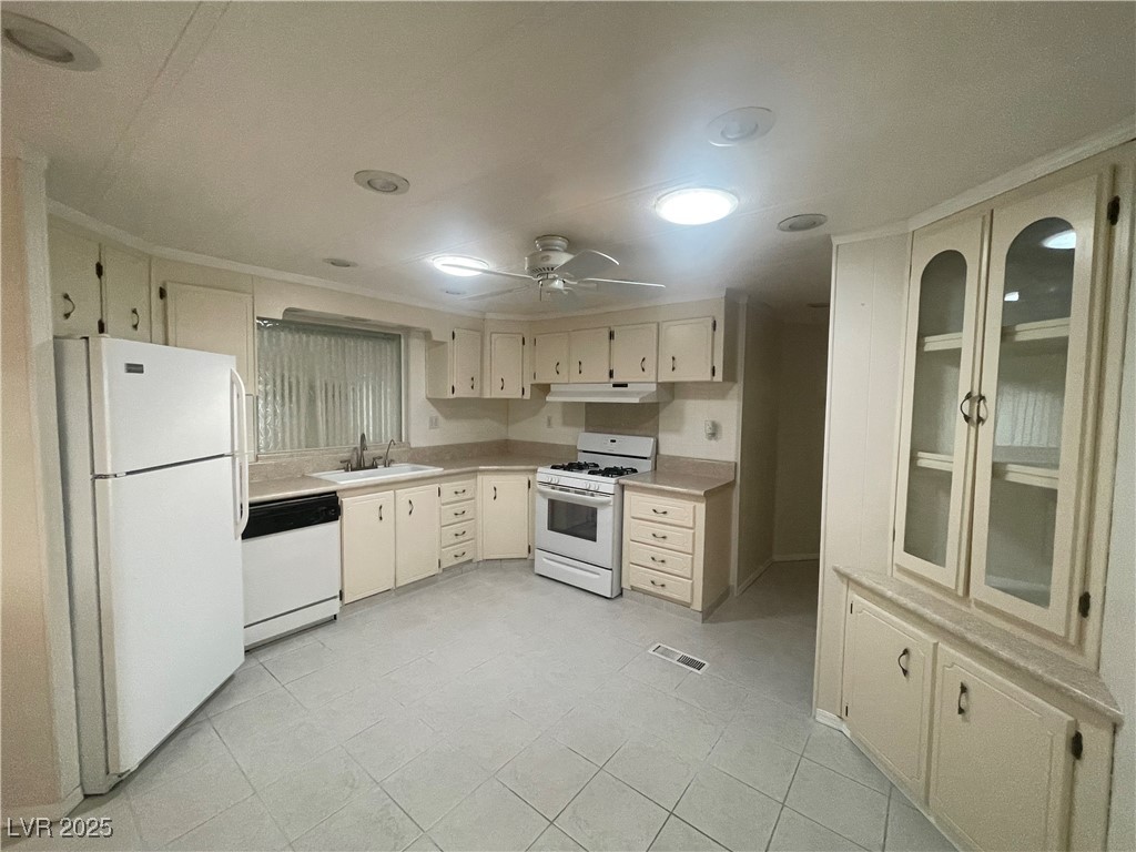 4641 Royal Ridge Boulevard Las Vegas, NV 89103 - Photo 15 of 38 Kitchen with white appliances, light countertops, ceiling fan, under cabinet range hood, and cream cabinetry