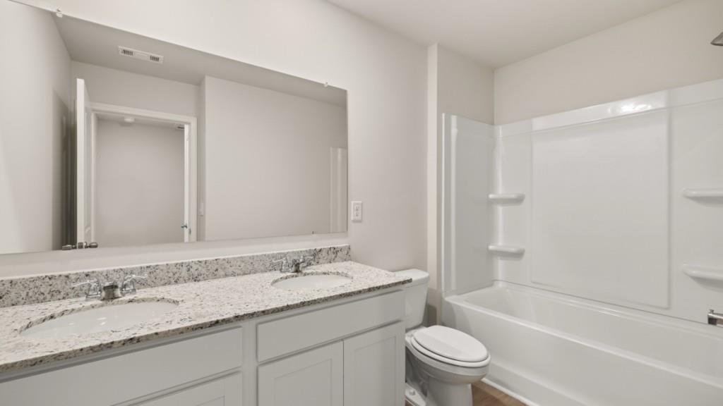 111 Babcock Drive Northeast Rome, GA 30165 - Photo 24 of 33 a bathroom with a granite countertop sink a toilet and a large mirror