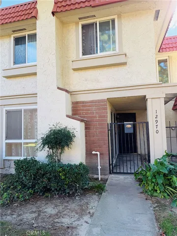 a view of a brick house with plants and large tree