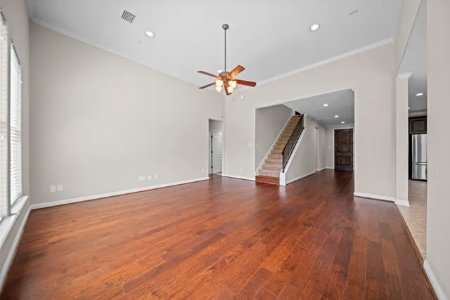 an empty room with wooden floor ceiling fan and a window