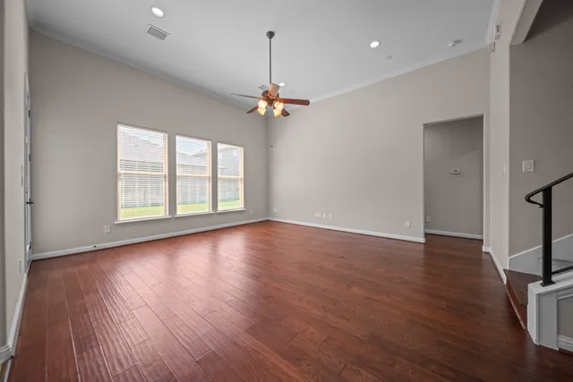 a view of an empty room with wooden floor and a window