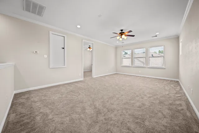 an empty room with chandelier fan and windows
