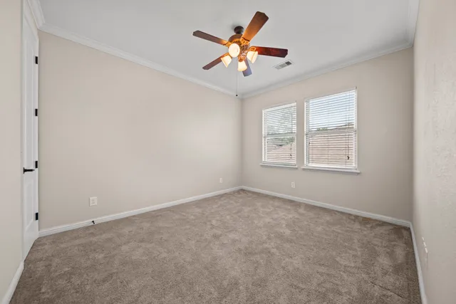 an empty room with ceiling fan and windows