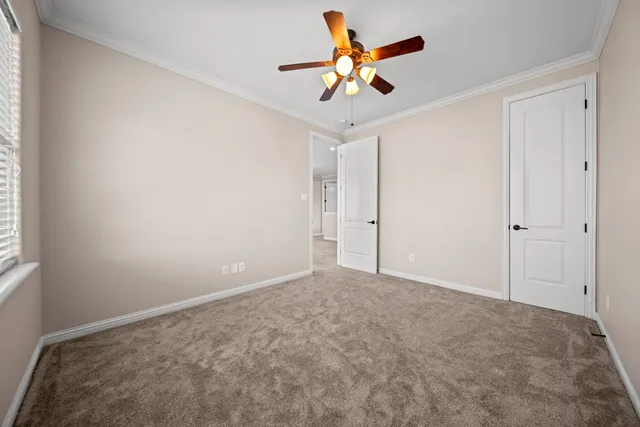 an empty room with a chandelier fan and closet