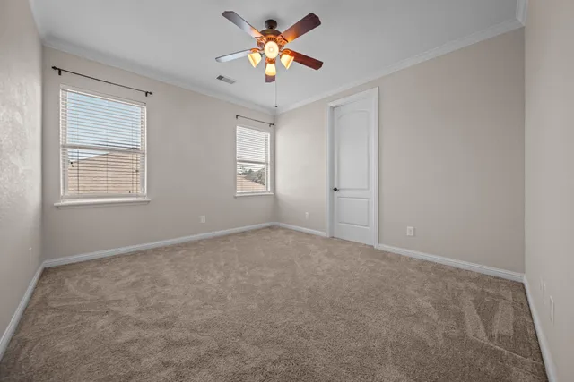 an empty room with windows and chandelier fan
