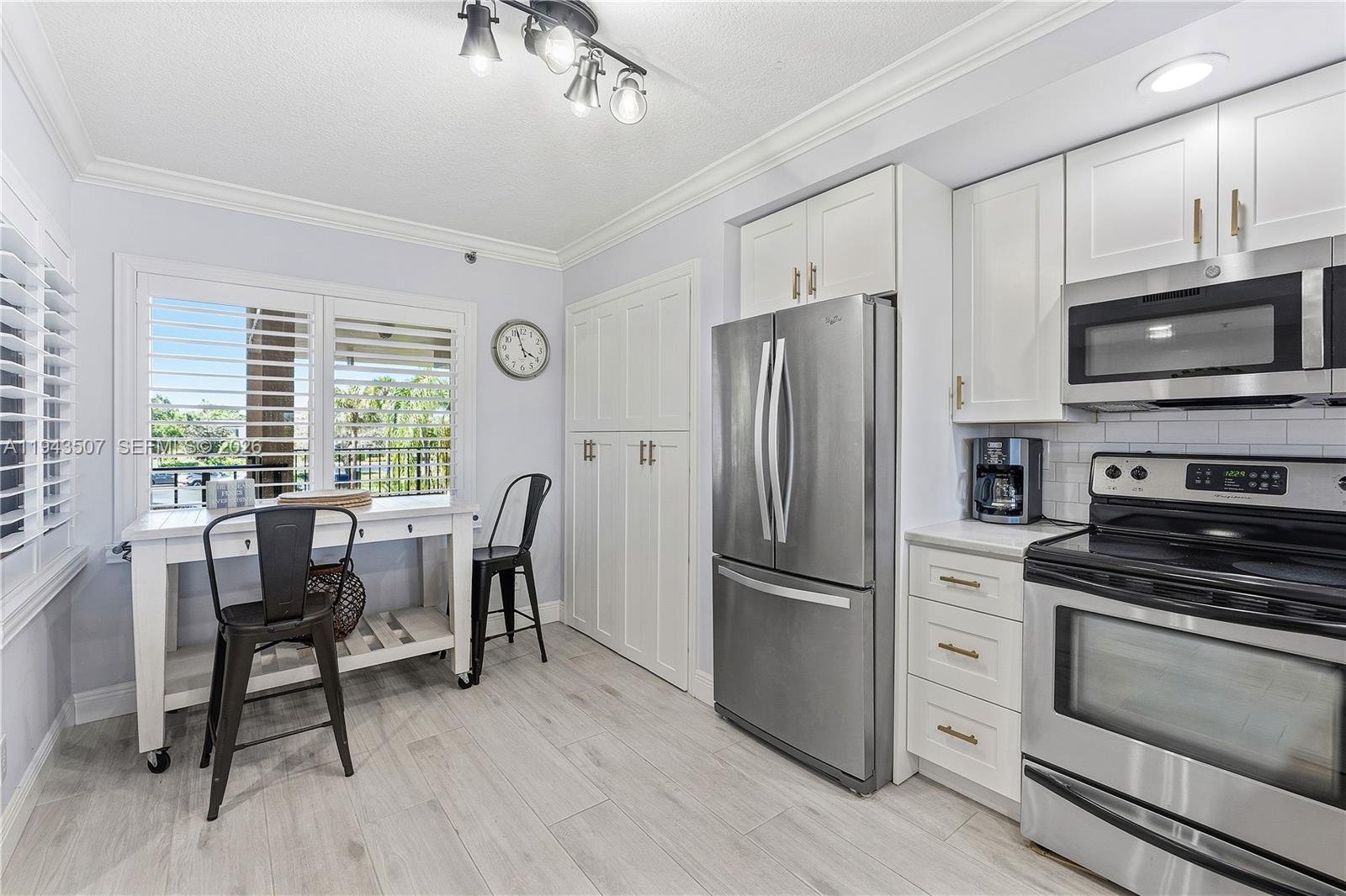 275 Palm Avenue, Unit B207 Jupiter, FL 33477 - Photo 2 of 29 a kitchen with stainless steel appliances granite countertop a stove a refrigerator a kitchen island a dining table and chairs with wooden floor