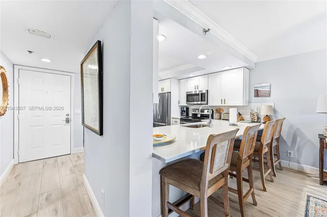 a kitchen with stainless steel appliances refrigerator dining table and chairs