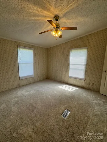 an empty room with windows and ceiling fan