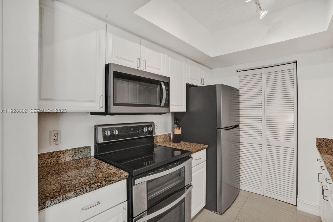 90 Alton Road, Unit 2907 Miami Beach, FL 33139 - Photo 13 of 42 a kitchen with granite countertop a refrigerator stove and microwave