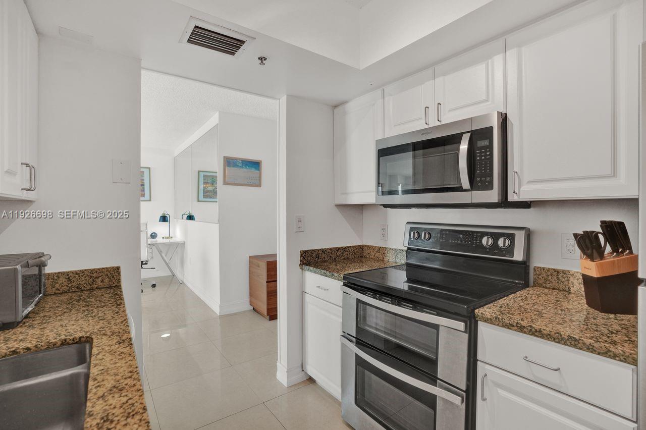 90 Alton Road, Unit 2907 Miami Beach, FL 33139 - Photo 15 of 42 a kitchen with stainless steel appliances granite countertop a stove microwave and refrigerator