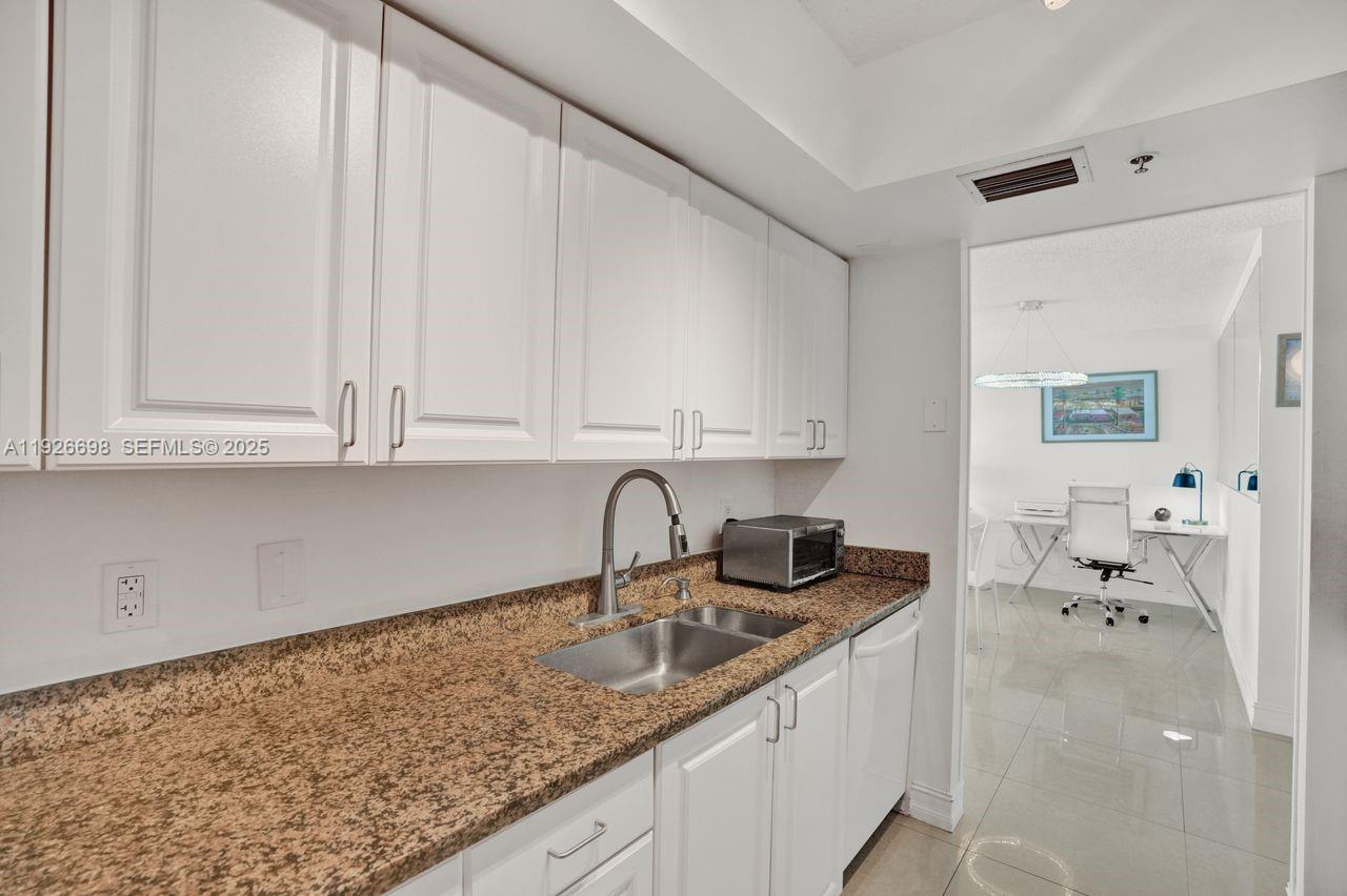 90 Alton Road, Unit 2907 Miami Beach, FL 33139 - Photo 32 of 42 a kitchen with granite countertop white cabinets and sink