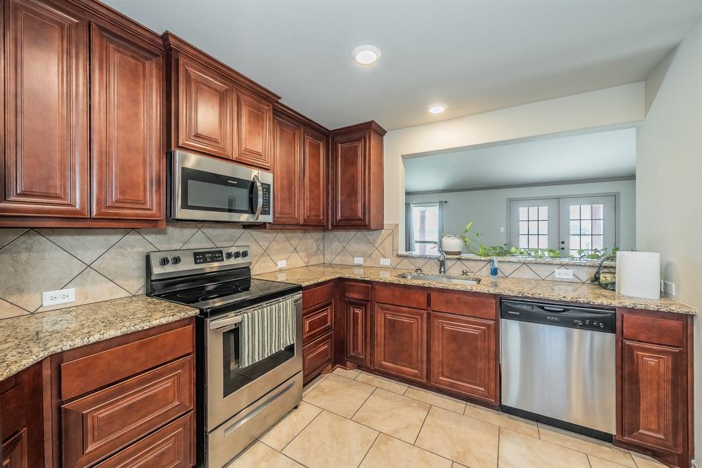 2376 Farm To Market Road 2264 Decatur, TX 76234 - Photo 25 of 39 a kitchen with stainless steel appliances granite countertop wooden cabinets a stove top oven a sink and dishwasher