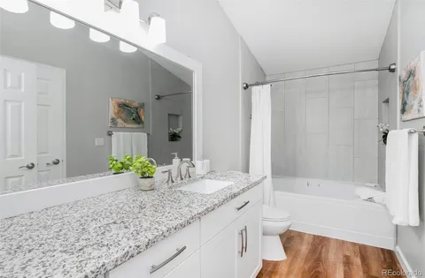 a bathroom with a granite countertop sink and a bathtub