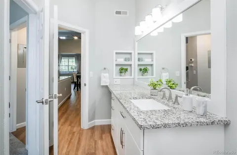 a bathroom with a granite countertop sink a mirror and a shower