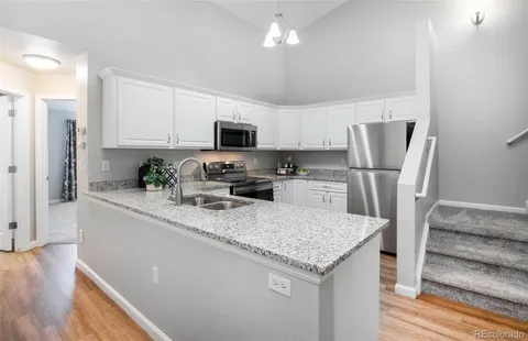 a kitchen with stainless steel appliances granite countertop a refrigerator a stove top oven a sink and dishwasher