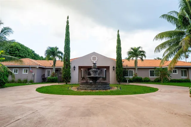 a front view of a house with a garden and trees