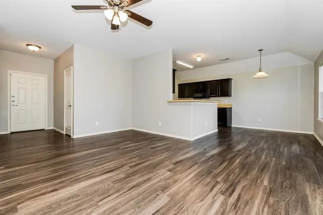 a view of empty room with wooden floor and ceiling fan