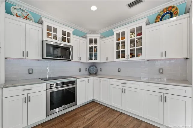 a kitchen with stainless steel appliances granite countertop a stove a sink dishwasher and a dining table with wooden floor