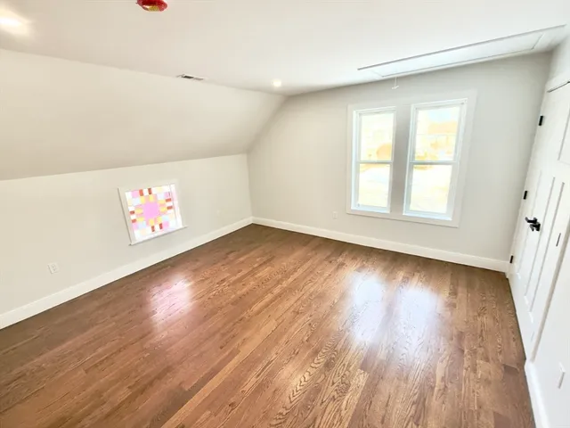 a view of a white house with a car parked in the road