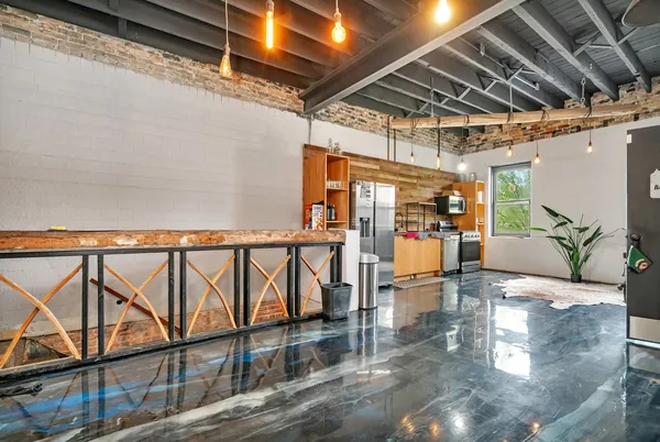 a living room with stainless steel appliances kitchen island granite countertop a table chairs and a wooden floor