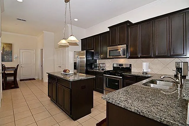 a kitchen with stainless steel appliances granite countertop a stove oven a sink dishwasher and a refrigerator with wooden cabinets