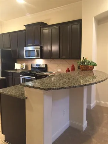 a kitchen with kitchen island granite countertop a sink a stove and cabinets