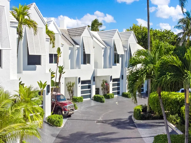a view of a white house with potted plants