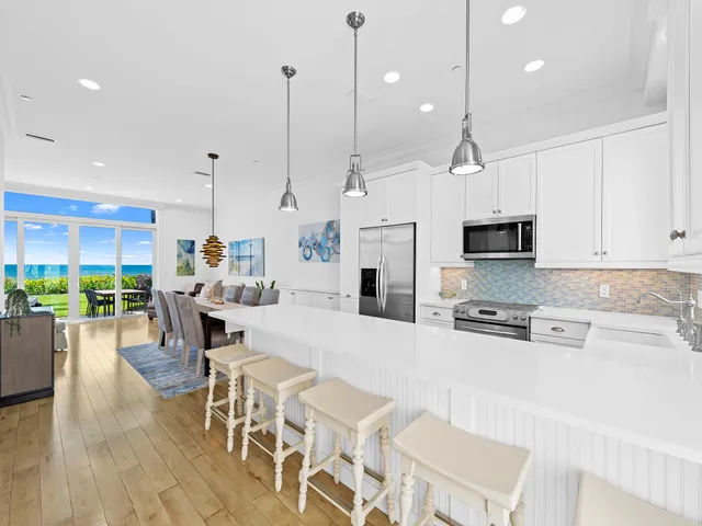a large kitchen with kitchen island granite countertop a stove a sink a center island a table and chairs