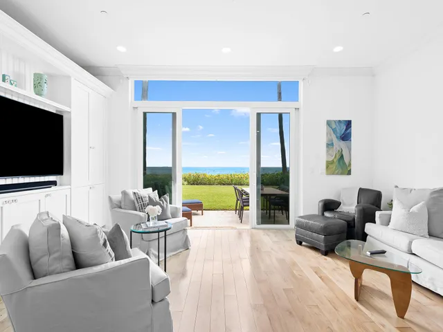 a living room with furniture floor to ceiling window and a flat screen tv