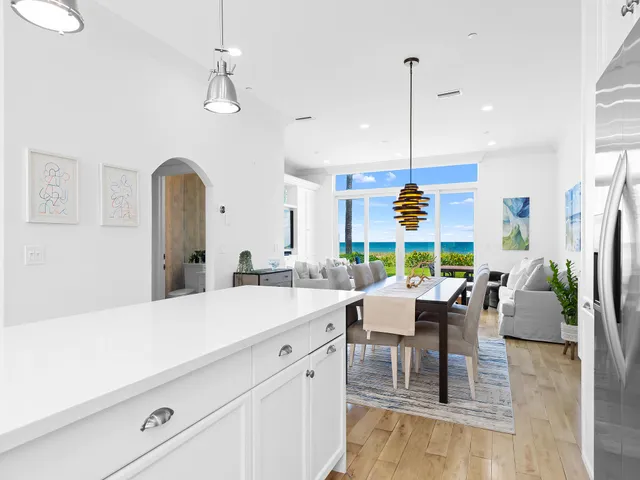 a room with stainless steel appliances kitchen island granite countertop a table chairs and a chandelier