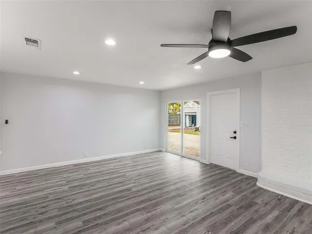 a view of a kitchen and an empty room with wooden floor