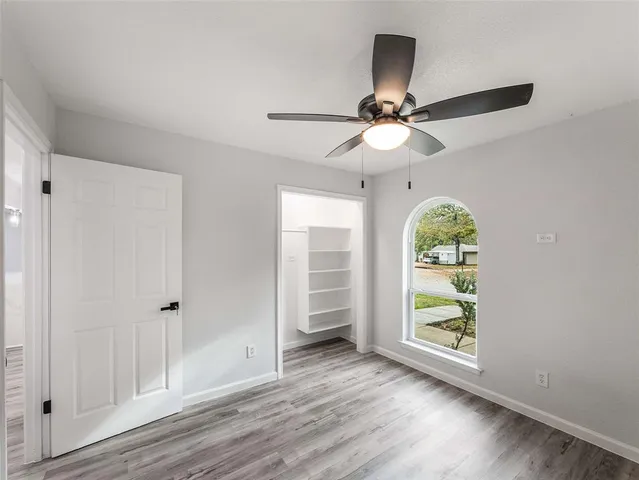 an empty room with ceiling fan and window