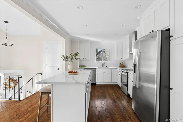 a kitchen with kitchen island white cabinets and stainless steel appliances