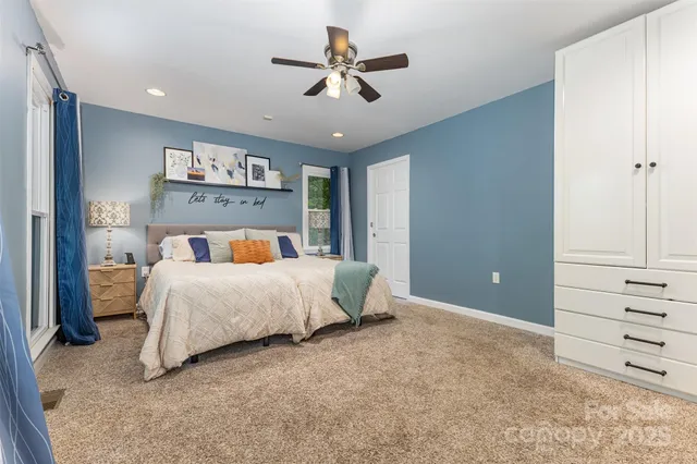 a bedroom with a large bed and a chandelier fan