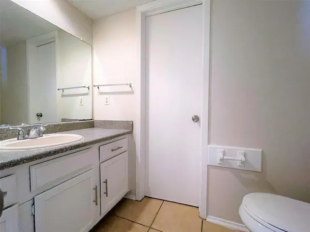 a bathroom with a granite countertop sink toilet and mirror