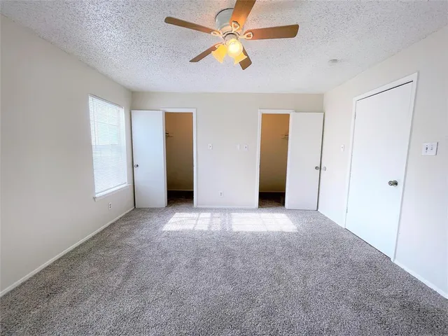 an empty room with closet and a chandelier fan