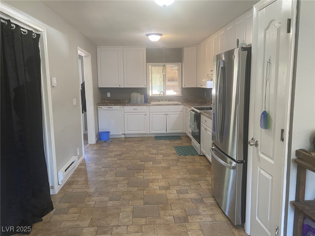 27 Carson Court Ely, NV 89301 - Photo 5 of 22 Kitchen with white appliances, white cabinetry, stone finish flooring, and a baseboard radiator