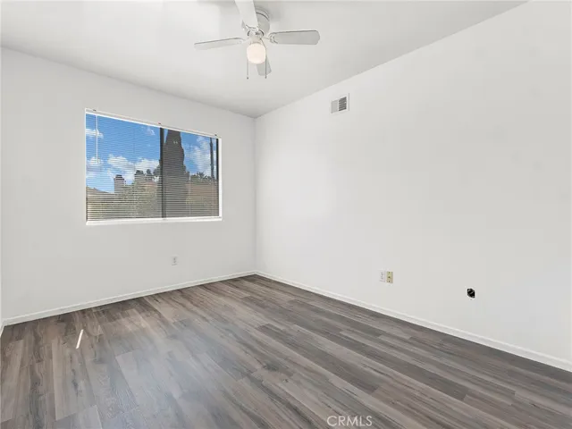 an empty room with wooden floor chandelier fan and windows