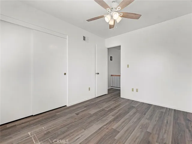 an empty room with wooden floor a ceiling fan and closet area