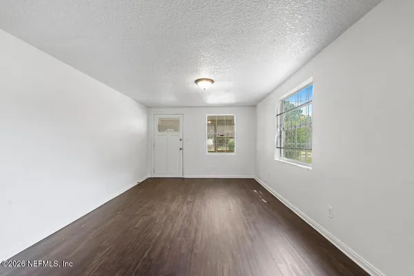 an empty room with wooden floor and windows