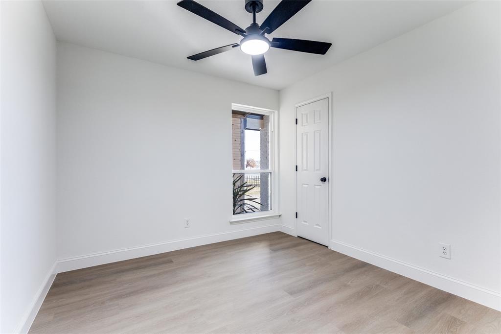 7609 Walnuthill Court Watauga, TX 76148 - Photo 15 of 22 an empty room with wooden floor ceiling fan and windows