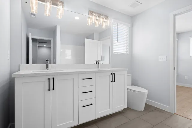 a bathroom with a double vanity sink a toilet and a mirror