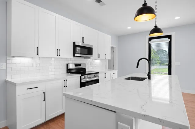 a kitchen with stainless steel appliances a sink a stove and a wooden floors