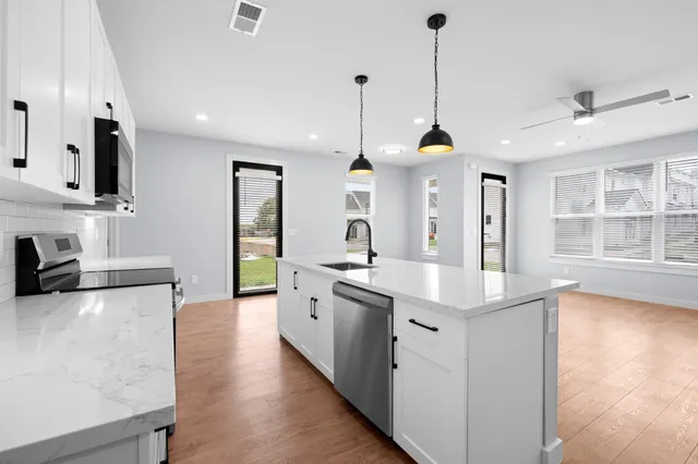 a kitchen with stainless steel appliances granite countertop a sink a stove and a wooden floor