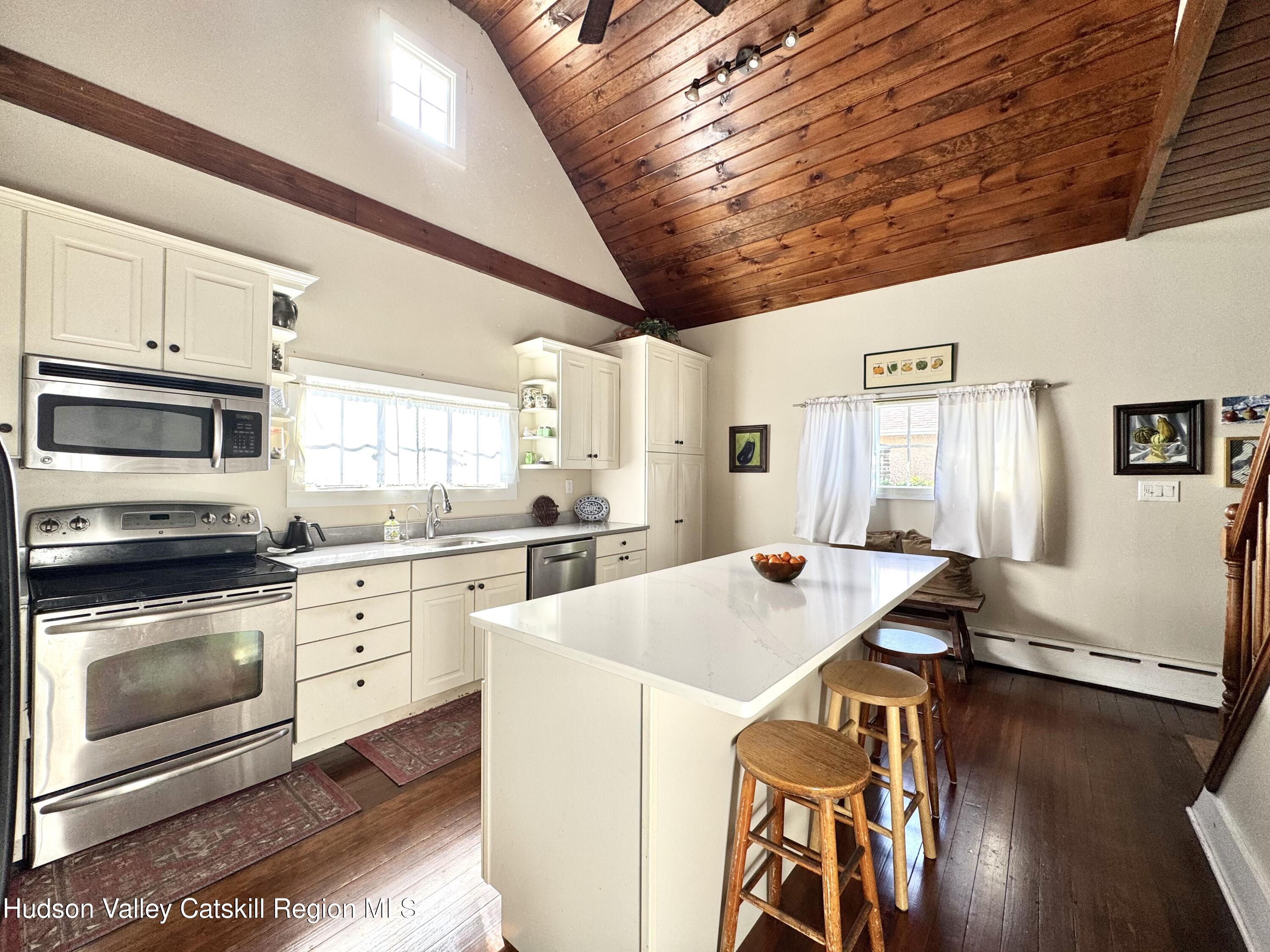 121 High Street Catskill, NY 12414 - Photo 11 of 29 a open kitchen with stainless steel appliances kitchen island granite countertop a stove a sink dishwasher and white cabinets with wooden floor