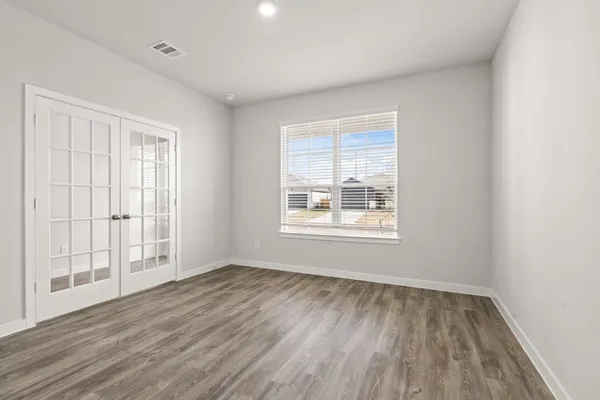 an empty room with wooden floor and windows