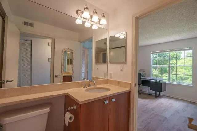 a spacious bathroom with a granite countertop sink a large mirror and a bathtub