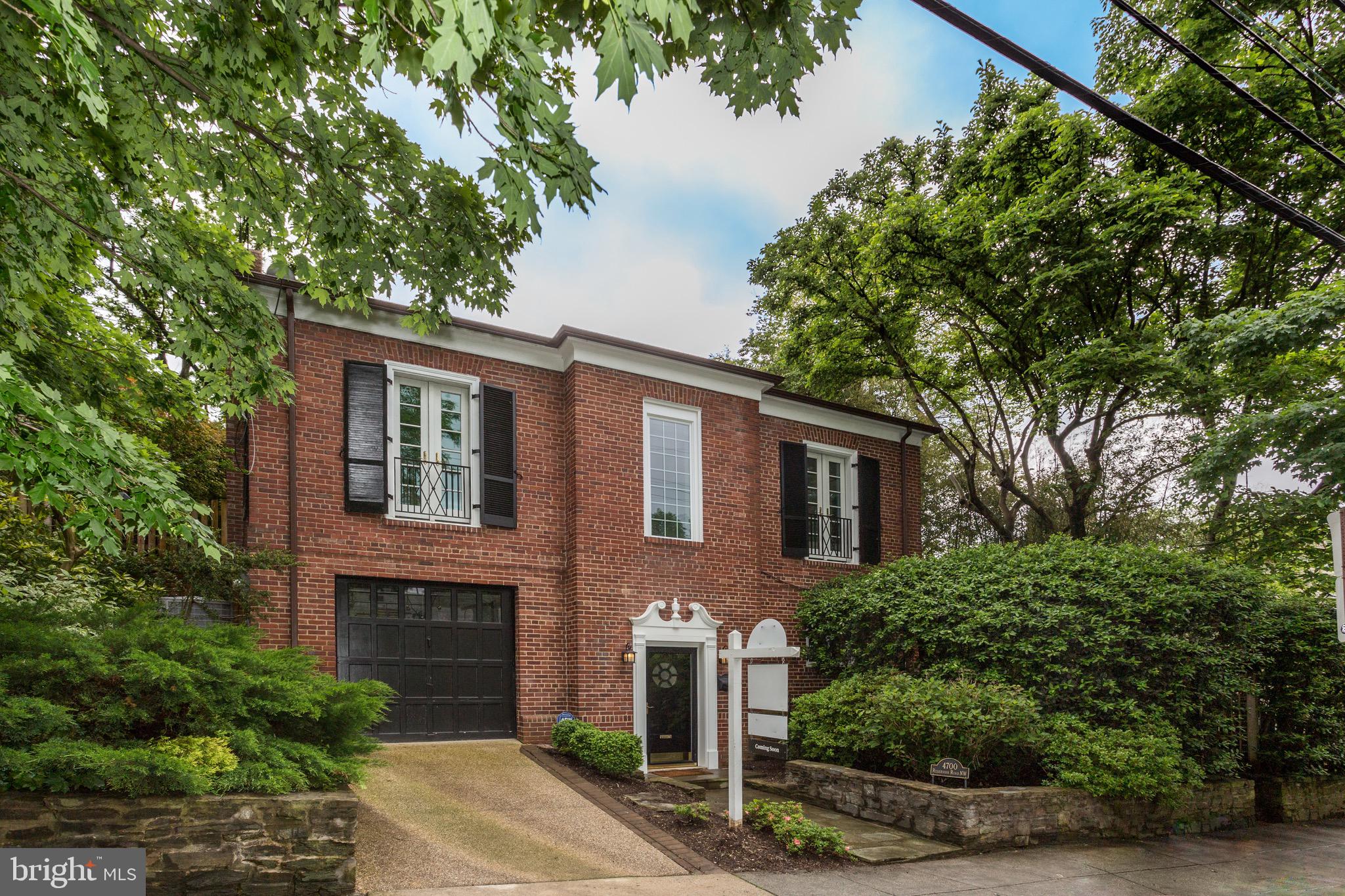 a front view of a house with plants and trees