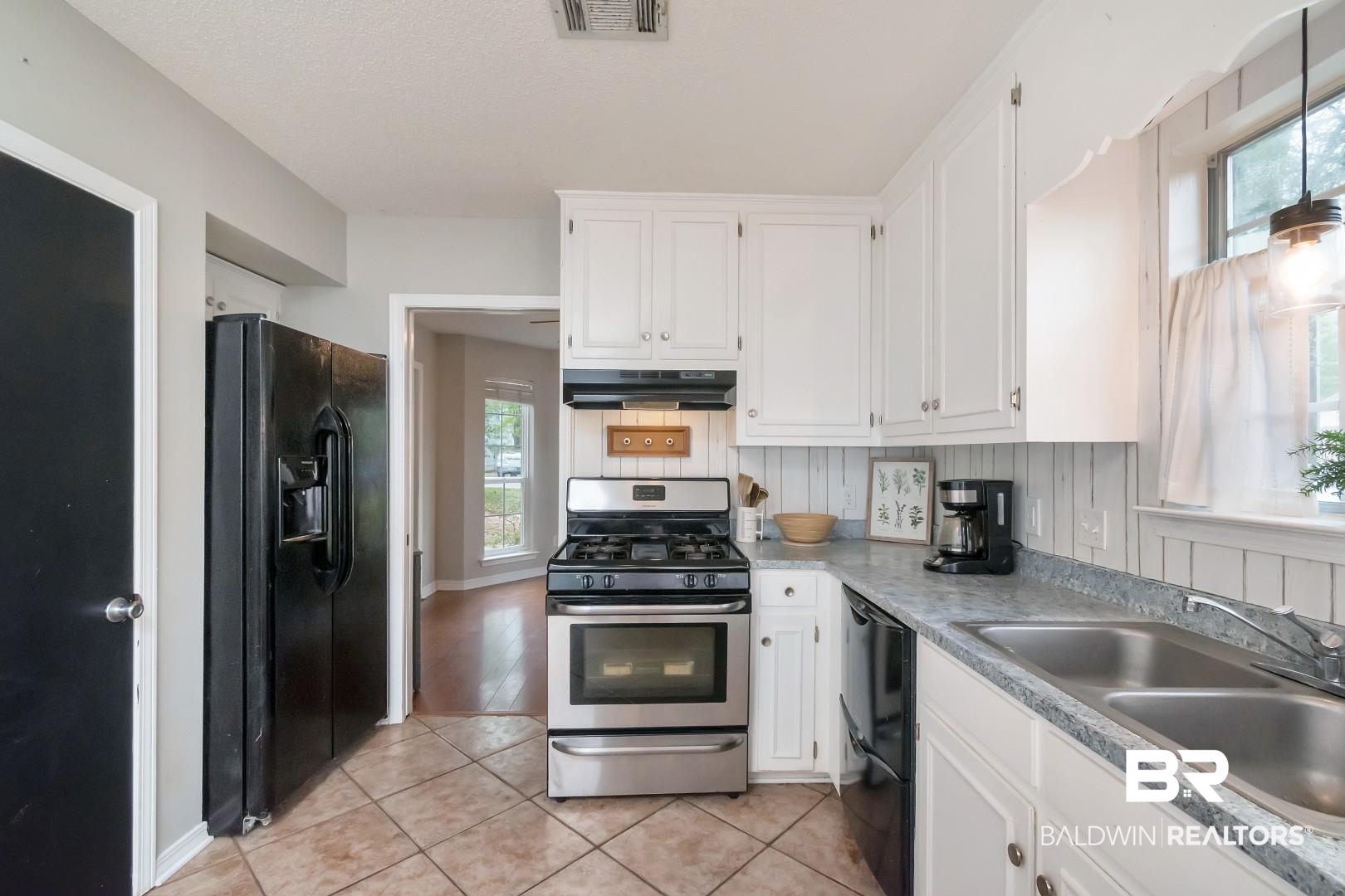 1065 Linlen Avenue Mobile, AL 36609 - Photo 9 of 31 Kitchen with a sink, white cabinets, under cabinet range hood, visible vents, and black appliances